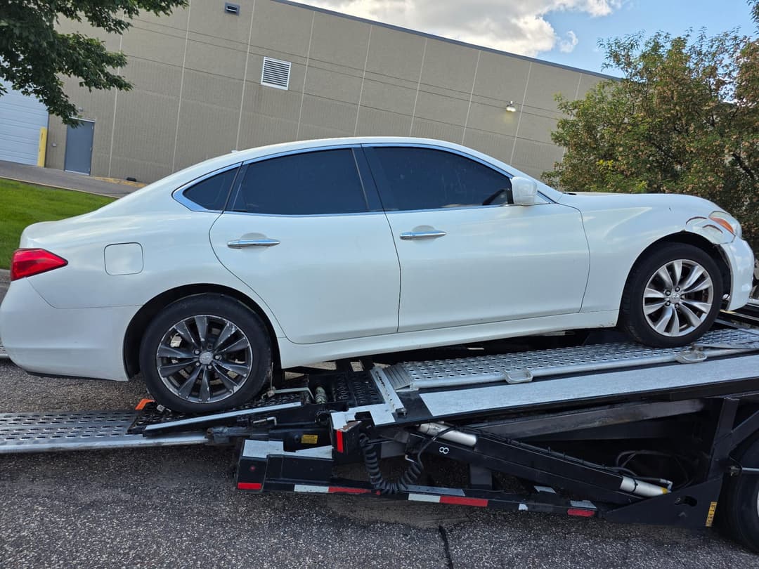 White sedan secured on flatbed tow truck during damage-free vehicle transport