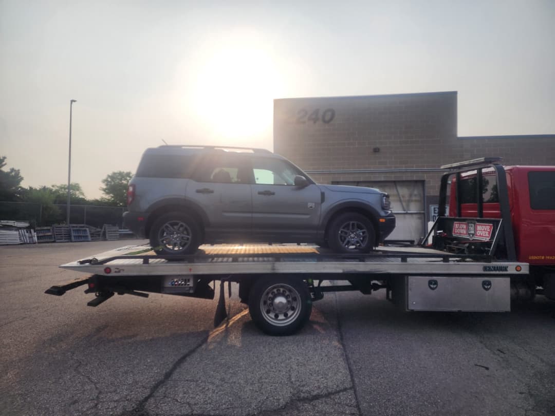 SUV being loaded onto flatbed tow truck for roadside towing service